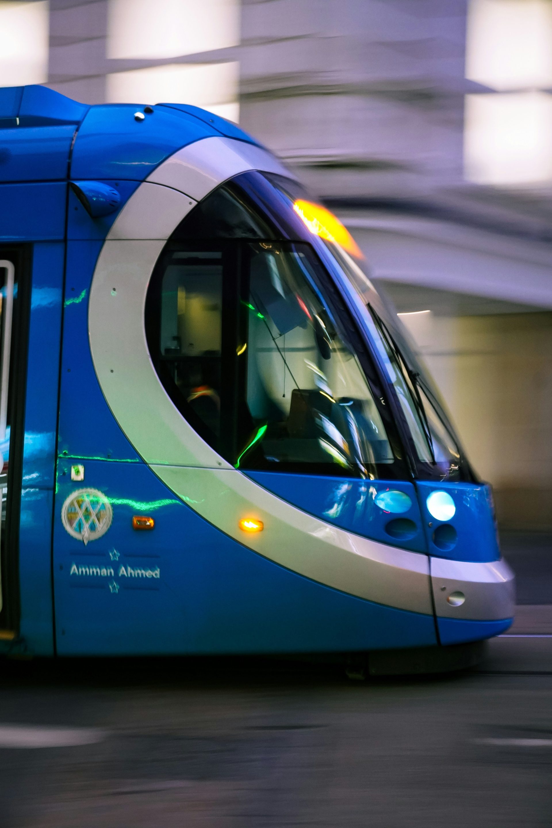 A blue train traveling down train tracks next to a tall building